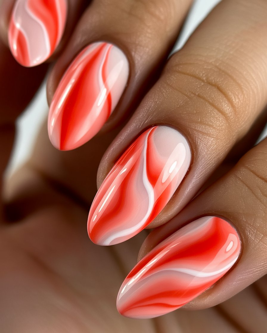 Coral marble nails with white and coral swirls for an artistic touch.