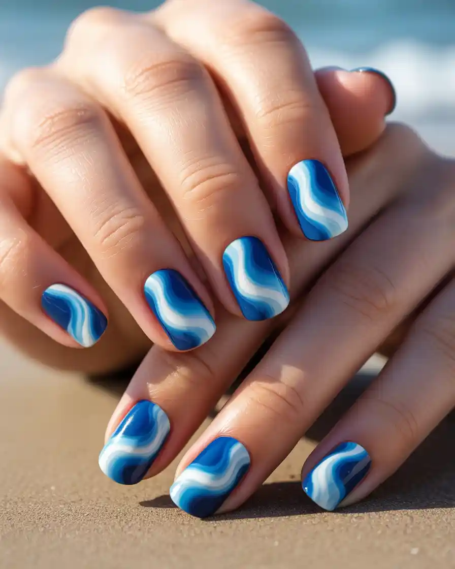 Ocean wave nail art with blue and white wave patterns.