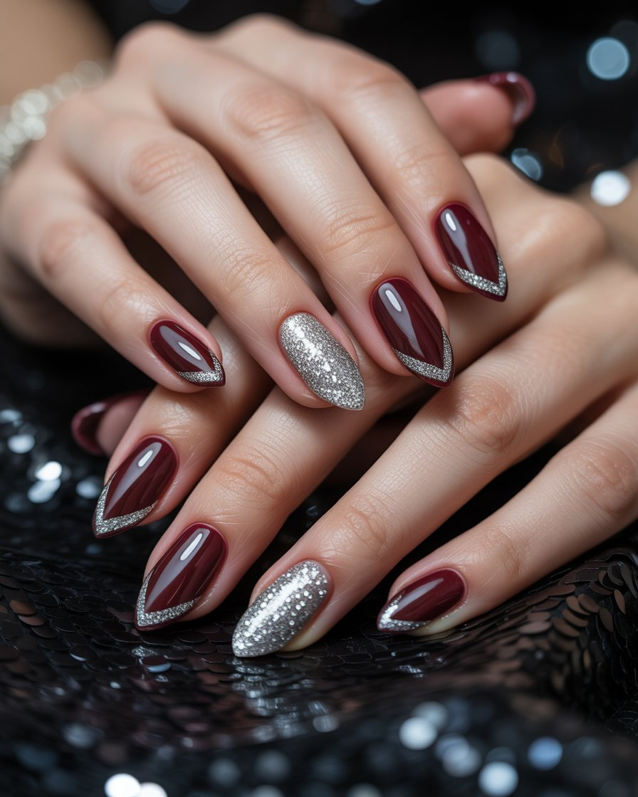 Close-up of burgundy chevron nails with silver glitter accents on a woman's hand.