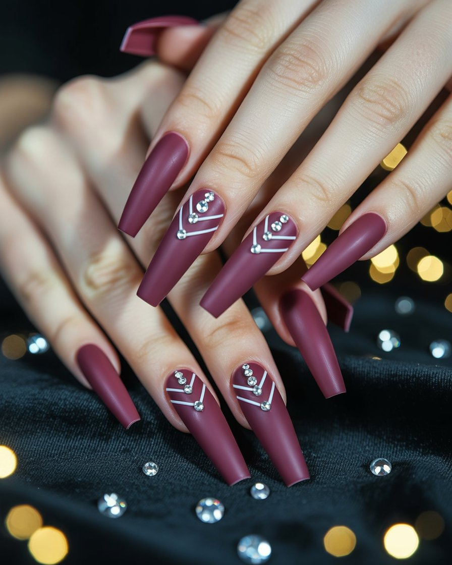 Matte burgundy chevron nails decorated with small rhinestones for an elegant look.