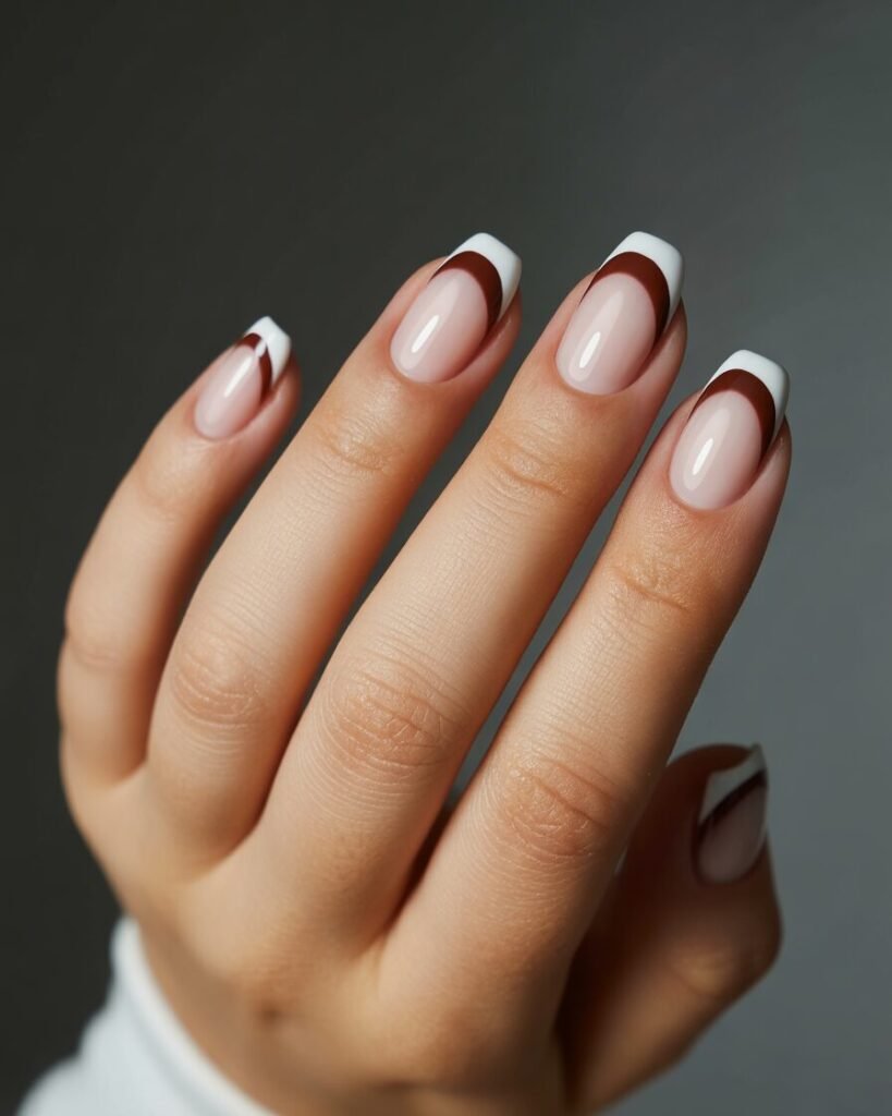 A hand with a manicure showing a soft fade from espresso brown to a creamy tip. The design is a stylish, modern take on a French manicure.